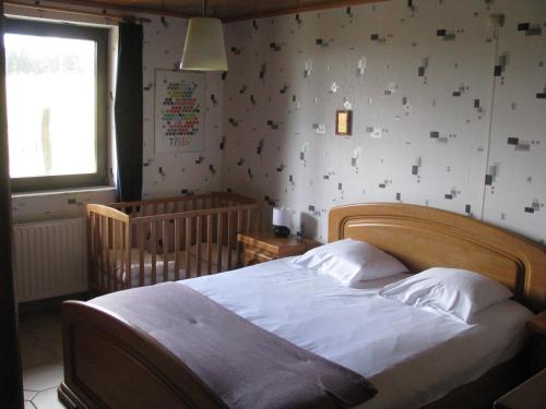 GouvyLa Maison du Bonheur的一间卧室配有一张大床和一张婴儿床。