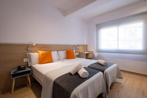 巴塞罗那三斯旅馆的卧室配有带橙色枕头的大型白色床