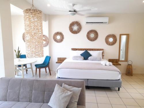 塔马林多Zulu Surf Hotel Tamarindo的一间卧室配有一张床、一张沙发和一张桌子