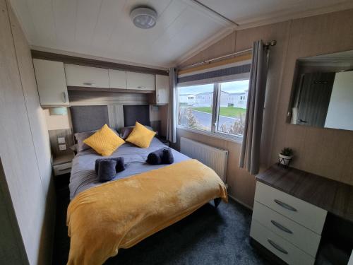 帕兹托Seven Sunsets, Padstow的一间卧室配有一张带黄色枕头的床和一扇窗户