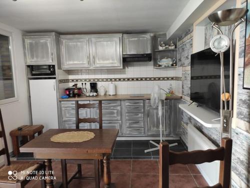 米利拉福雷Maison avec deux chambres au calme的厨房配有白色橱柜和木桌