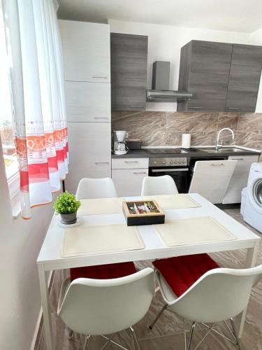 奥帕提亚Apartment Marina的厨房配有白色的桌子和白色的椅子