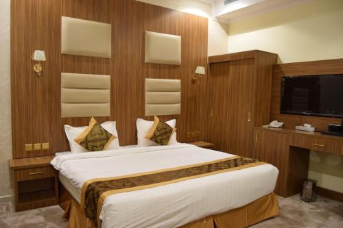 Sīdī Ḩamzahفندق اللؤلؤة الذهبي的一间带大床和电视的卧室