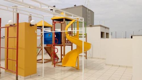 齐克拉约Hermoso Departamento dentro de un Condominio的大楼内一个带黄色滑梯的游乐场