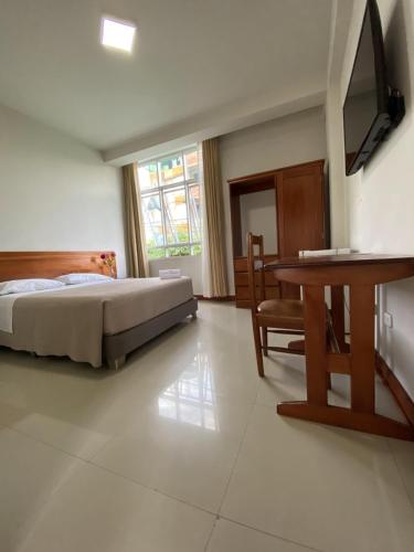 马尔多纳多港Hotel Peru Amazonico的一间卧室配有一张床、一张桌子和一张书桌