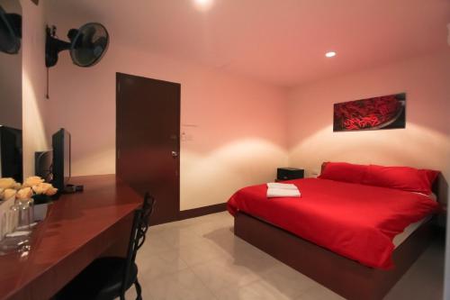南芭堤雅步行街旅馆的一间卧室配有红色的床和一张书桌
