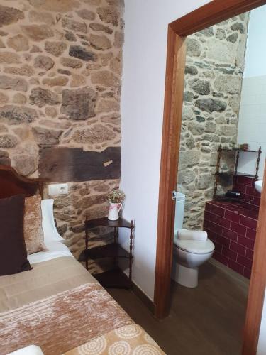 帕拉斯德丽La Pallota de San Cristobal的一间带石墙、一张床和卫生间的卧室