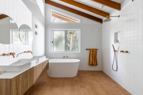 萨福克公园Blackbutt House - Luxe Family Retreat With Pool的带浴缸、两个盥洗盆和窗户的浴室