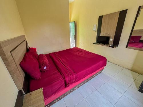 SampitGreenville Hotel Mitra RedDoorz的一间带电视的客房内的一张红色床铺