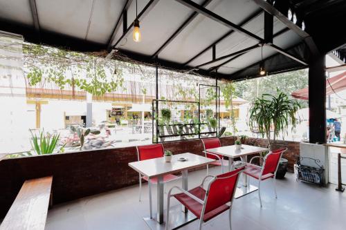 茉莉芬RedDoorz near Alun Alun Madiun的餐厅设有红色的桌椅和大窗户