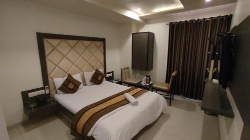 艾哈迈达巴德Hotel Flair Inn的一间卧室配有一张大床和电视