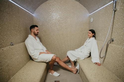 苏博蒂察Artist hotel的坐在淋浴椅上的男人和女人