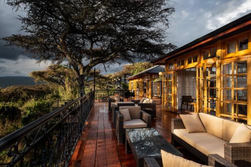 恩戈罗恩戈罗Lions Paw Ngorongoro的阳台,带沙发和椅子的建筑