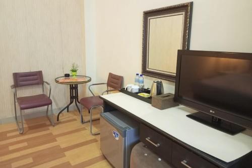 KelianUrbanview Hotel Yasminstar Muntok的酒店客房配有电视、桌子和椅子。
