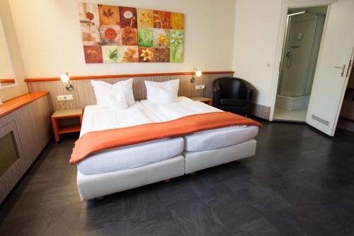 科隆Trip Inn Hotel Ariane的一间卧室配有一张大白色床和橙色毯子