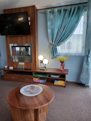 SeasalterVista Caravan Hire的客厅配有桌子和电视