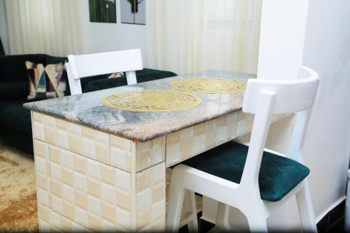 坎帕拉Igwe Homes - Kisaasi的一张桌子,配有两把白色椅子和台面