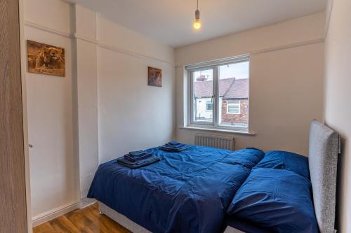 利物浦Cheerful and modern 3 BDR for 7的一间卧室配有一张带蓝色床单的床和一扇窗户。