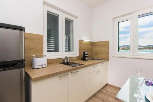 克拉帕尼岛Riva 2的厨房配有白色橱柜、冰箱和窗户。
