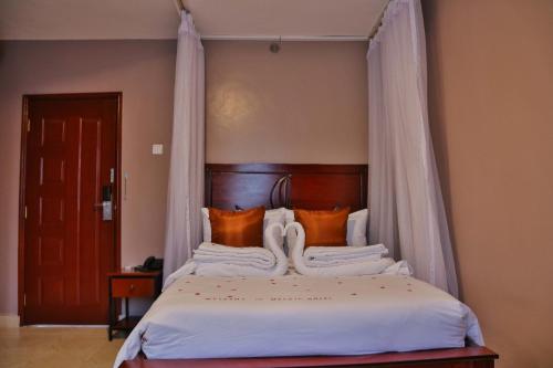 基苏木Melvic Hotel的一间卧室配有带橙色枕头的天蓬床
