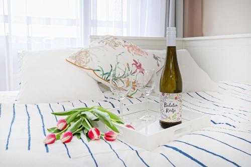 希欧福克Silver Lodge Ezüstpart Apartman的床上有一瓶葡萄酒和一杯玻璃及鲜花