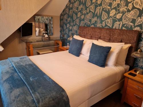 布里克瑟姆Brookside Guest House & Mini Spa的一间卧室配有一张带蓝色枕头的大床
