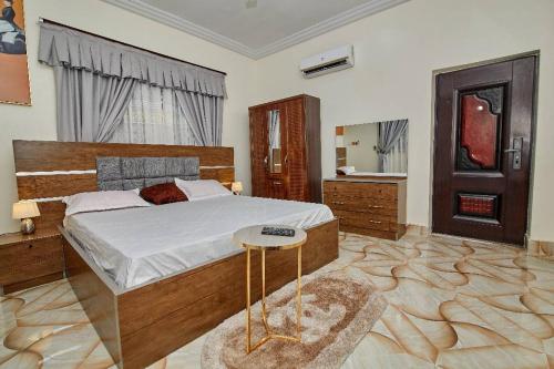库马西Pomaa Villa的一间卧室配有一张大床和一张桌子