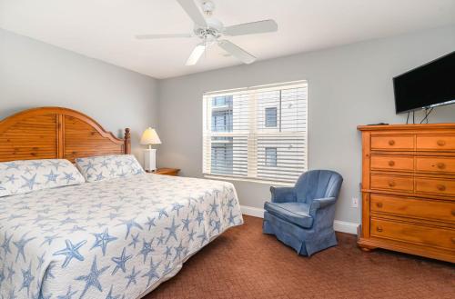 默特尔比奇Spacious Penthouse Ocean Front 7 BR Condo - Ambassador Villas Unit 401的一间卧室配有一张床、一把椅子和吊扇