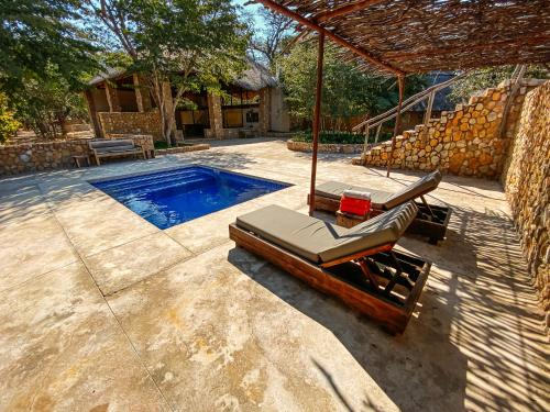 DeteGwango Elephant Lodge的一座房子旁的游泳池,配有两把躺椅