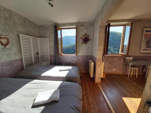 Roubion雷皮卡布拉民宿的一间卧室配有两张床、一张桌子和两个窗户。