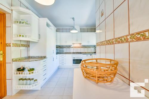 卡尔佩Villa Angeles - Grupo Turis的厨房配有白色橱柜和藤椅