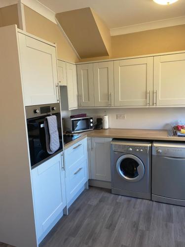 锡豪西斯Sea Haven Northumberland的厨房配有白色橱柜、洗衣机和烘干机