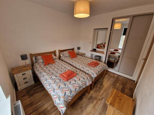 斯基普顿Albert Cottage的一间卧室配有两张带橙色枕头的床