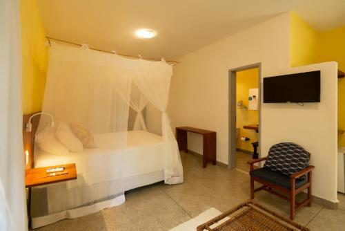 托兰克索Travel Inn Trancoso Suítes的一间卧室配有一张床、一把椅子和电视