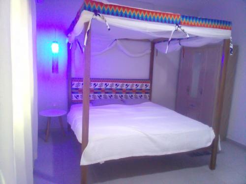 阿克拉Kokrobitey Apartments-GAL的一间卧室配有一张带紫色灯的天蓬床