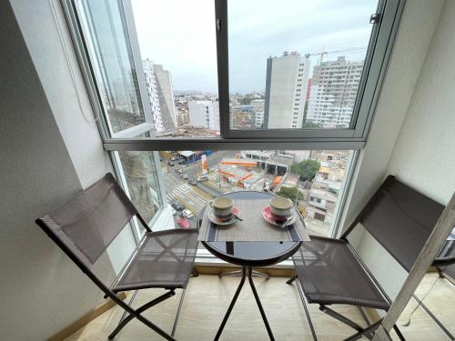 利马Habitación privada con hermosa vista de Barranco的窗前的一张桌子和两把椅子