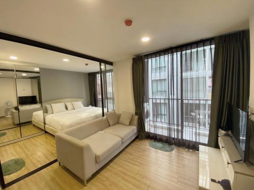 GodownNotthing Hill Charoenkrung93 Condominium的一间卧室配有一张床、一张沙发和一台电视。