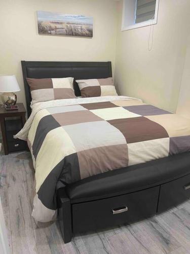 布兰普顿Adorable1-Bedroom Basement apartment, free parking的一间卧室配有一张棕色和白色的被子的床