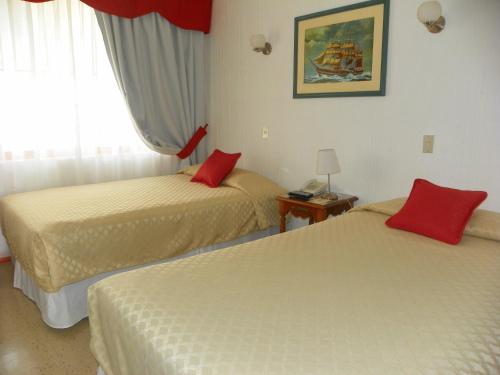 阿里卡萨沃纳酒店的两张位于酒店客房的床铺,配有红色枕头