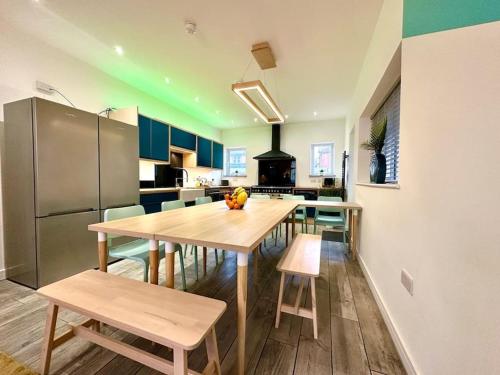 伯恩茅斯Massive New 8 bedroom House Sleeps up to 21 - Accepts Groups - Great Location - FREE Parking - Fast WiFi - Smart TVs - sleeps up to 21 people - Close to Bournemouth & Poole Town Centre & Sandbanks的厨房配有桌椅和冰箱。