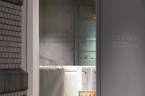 京都TSUGU Kyoto Sanjo by THE SHARE HOTELS的浴室设有悬挂在窗户上的白色毛巾
