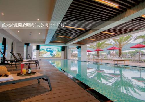 头城兰阳乌石港海景酒店的大楼内带桌子和遮阳伞的游泳池
