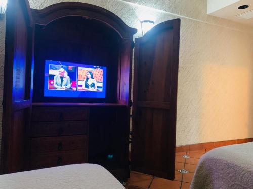 马塔莫罗斯HOTEL COLONIAL MATAMOROS的一间带木柜内电视的卧室
