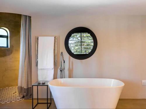 斯泰伦博斯Devon Castle Forest Lodge的带窗户的浴室内的白色浴缸