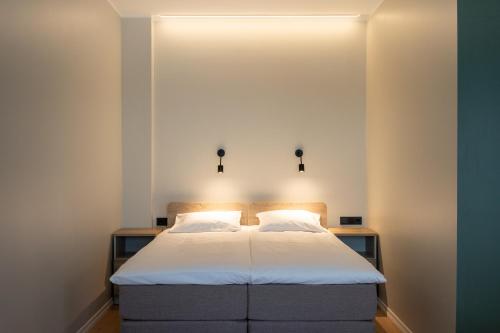 塔林Espak Hostel的一间卧室配有白色床单和灯。