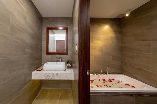 岘港K Hotel Sauna and Massage的浴室配有浴缸和带红色鲜花的盥洗盆。
