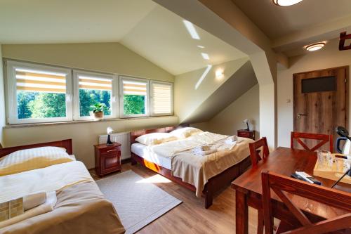 WańkowaHotel BIESZCZADski Wańkowa的一间卧室设有两张床、一张桌子和两个窗户。
