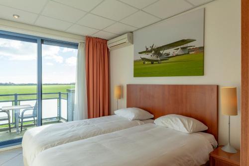 德科克斯多普Studio's De Vlijt Texel的卧室配有一张床,墙上挂有飞机