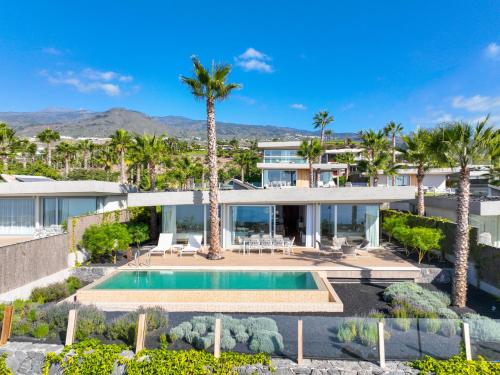 吉亚德伊索拉Los Jardines de Abama Suites的享有带游泳池和棕榈树的别墅的空中景致
