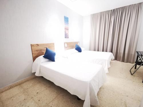 拉克鲁斯Hotel Don Cándido的一间卧室配有两张带蓝色枕头的床